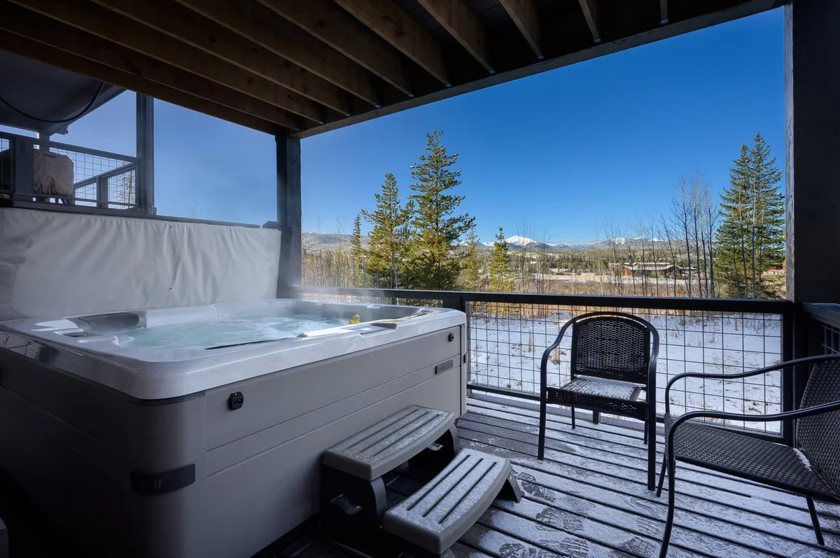 A covered upper deck furnished with a hot tub and comfortable seating, opening up to sweeping mountain views. The tranquil outdoor space is ideal for socializing, morning coffee, or après-ski relaxation while soaking in the scenery.