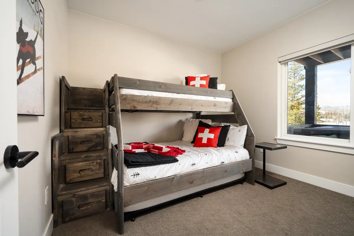 A playful bunk room with a twin-over-full bunk bed, decorative pillows, and a window offering cheerful natural light. The setup is clearly designed for kids, with a welcoming, adventure-ready vibe.