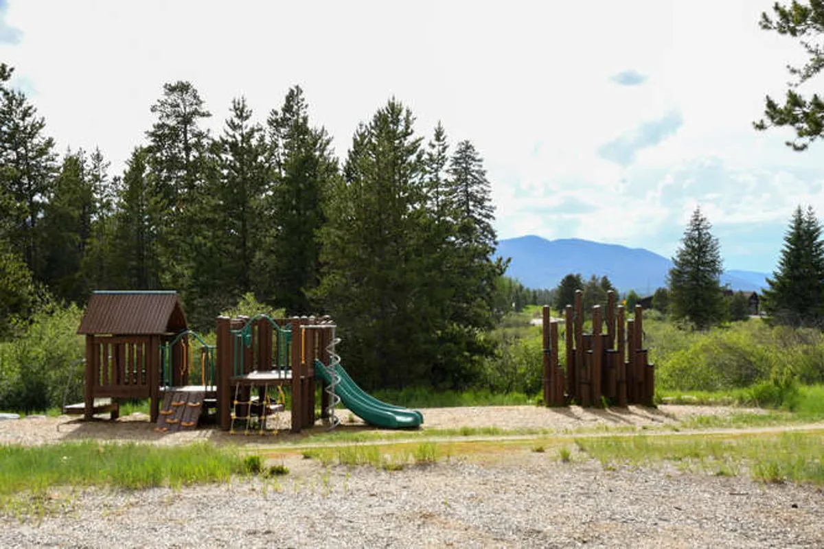 A vibrant playground structure with slides and climbing apparatus sits outdoors, inviting kids and families to play. The setting blends natural elements and open space, ideal for family fun steps from home.